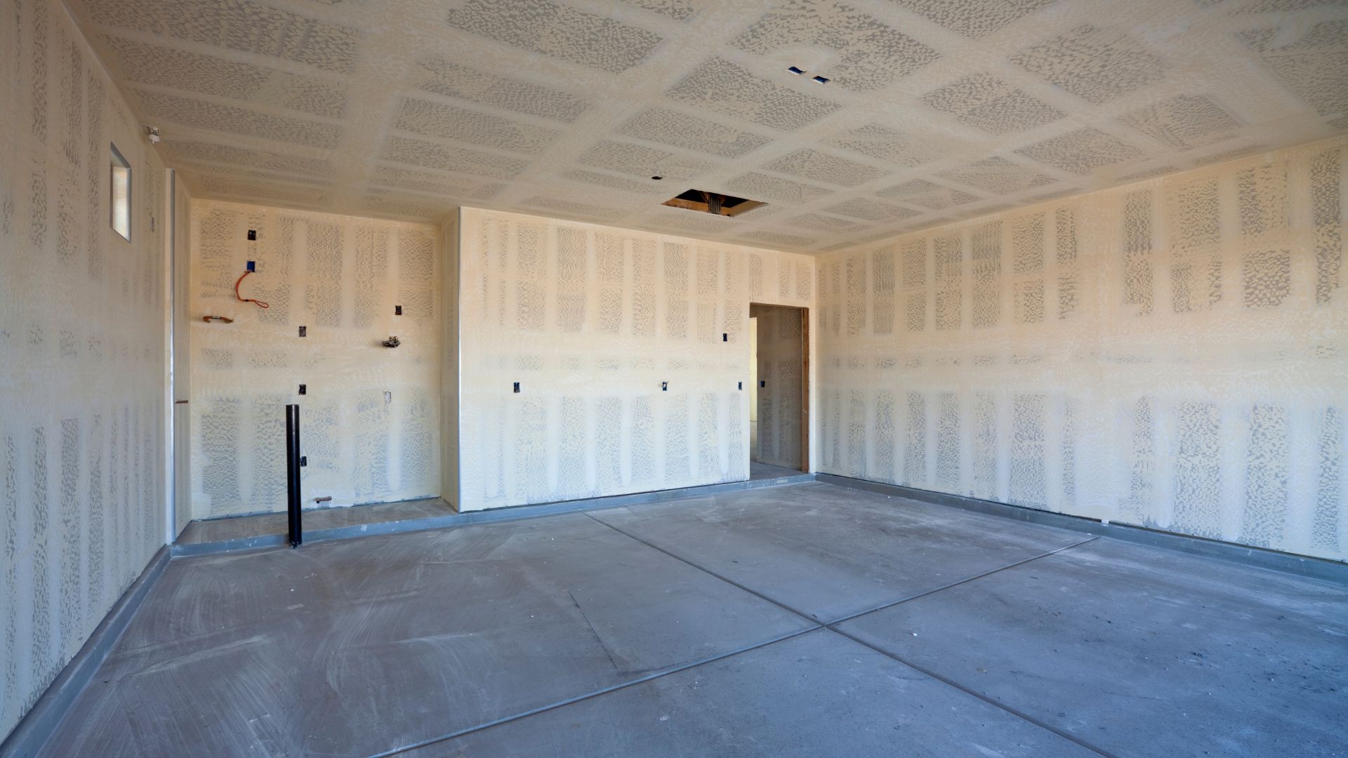 Unfinished room with textured white walls and concrete floor