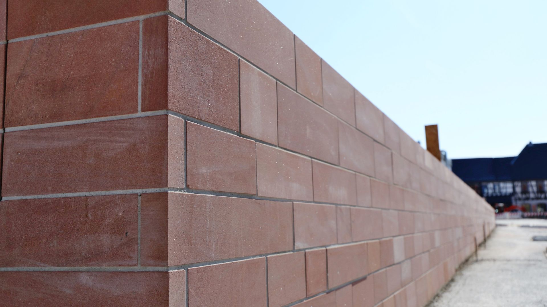 Long reddish-brown brick wall with clean lines extending into distance