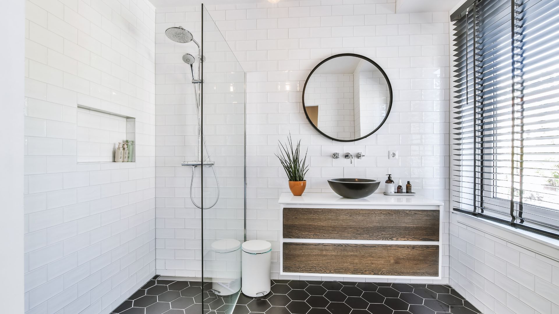 Modern white bathroom with glass shower, wood vanity, and hexagonal floor tiles