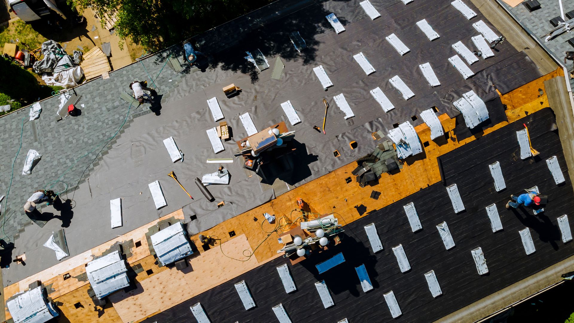 Aerial view of roofing workers installing shingles on a residential roof