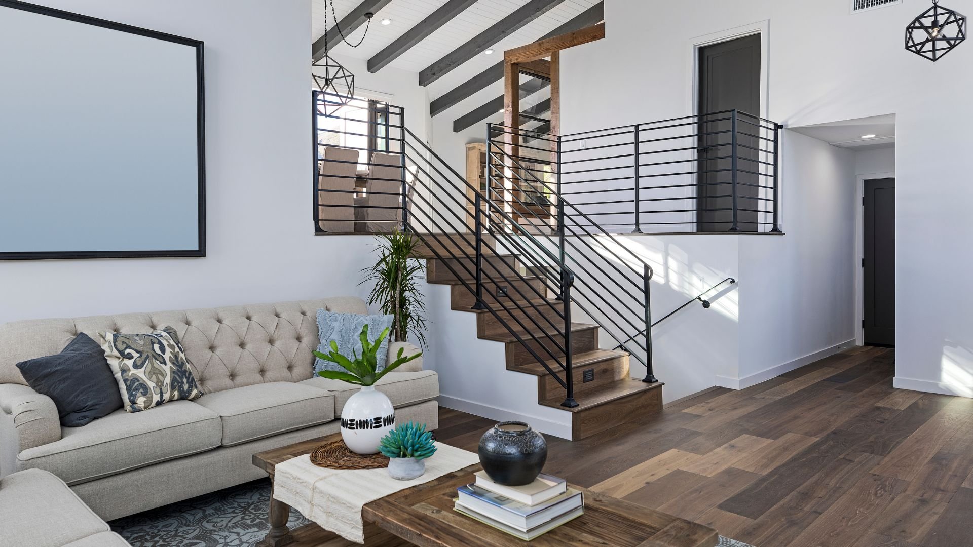 Modern living room with tufted sofa, wooden stairs, and geometric decor
