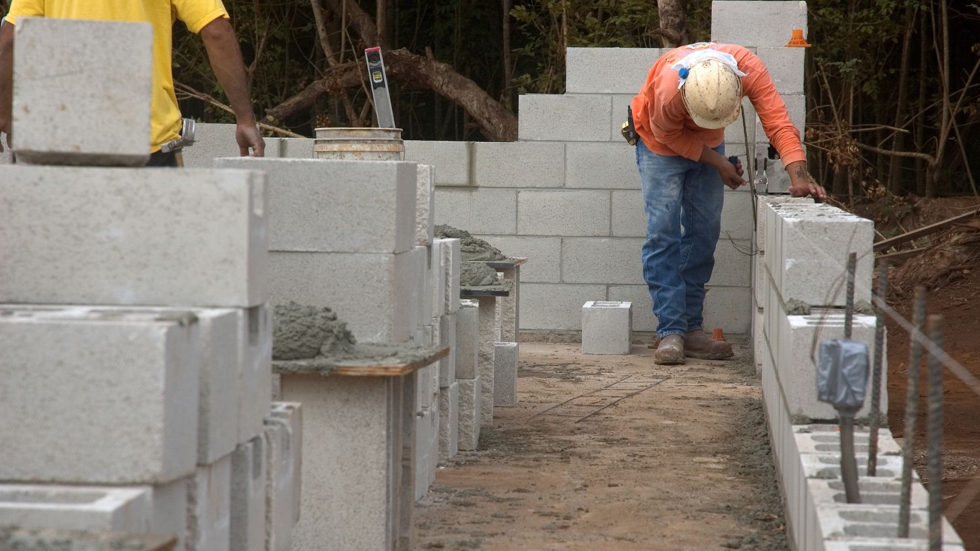 Construction workers building concrete block wall on building site