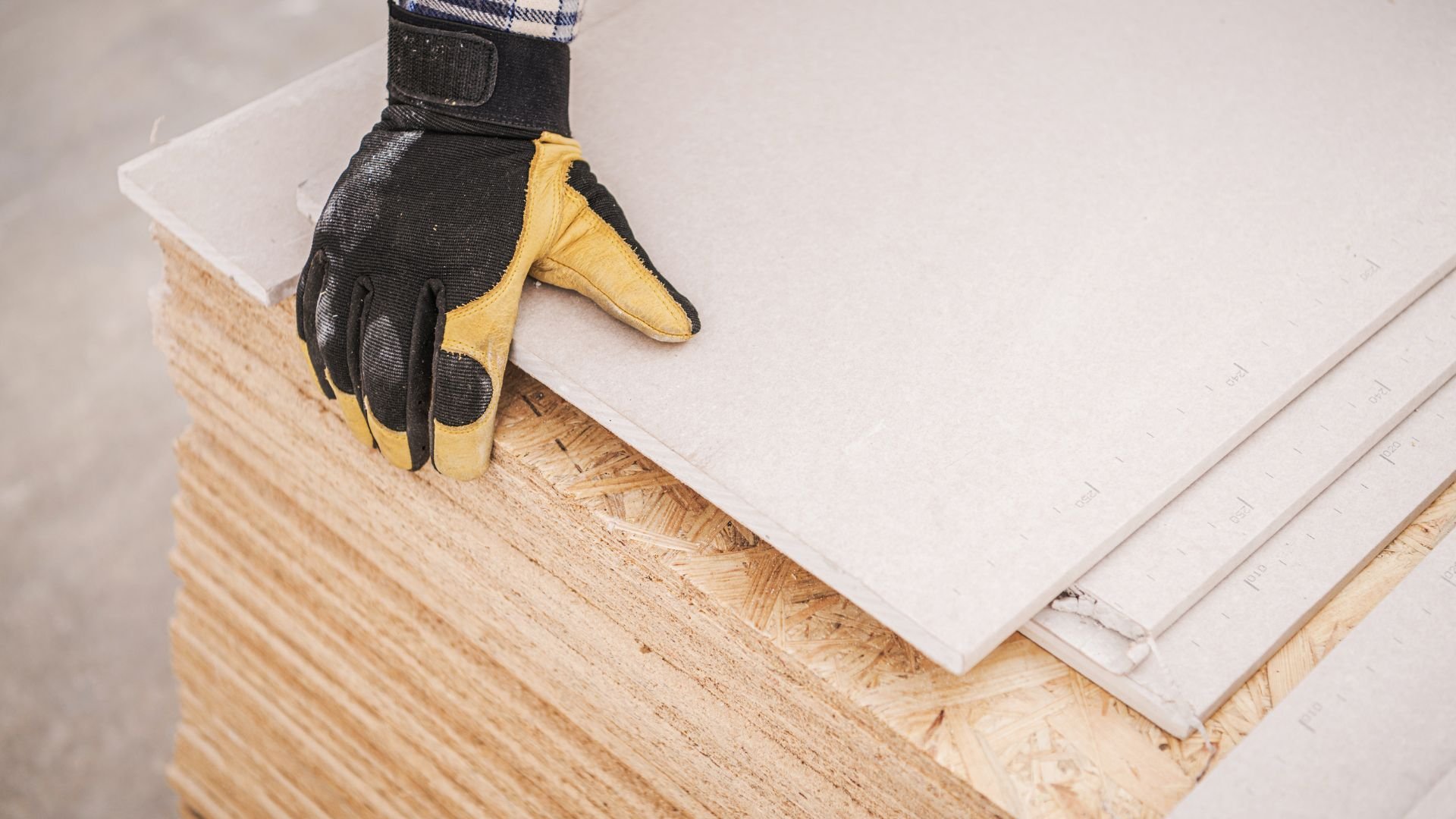 Work glove resting on plywood sheets during construction or renovation